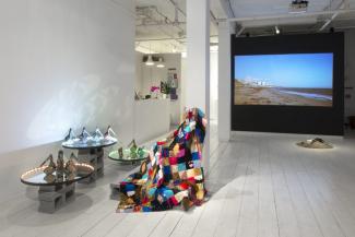installation view of video, quilt, and ceramics shoes on a mirror platform installed in a gallery