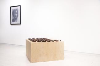 wooden blocks on a wooden plinth with a print on the wall behind