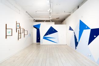 installation view of wall paintings with geometric shapes in various blues and sculptural objects