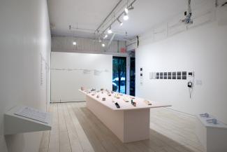 Installation views of sculptural objects on a long pale pink plinth