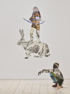 Installation of collaged work on the wall and extending into the space as 2D sculptures, featuring a hunter standing on a hare's back, and a crouching boy.