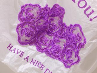 Close-up image of beaded roses in fuchsia on a plastic bag.