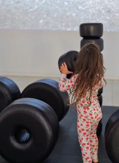 Image of a long-haired child in cherry-print pyjamas playing with Carrie Allison's BIG BEADZ while watching a projected video.