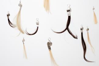 Whistles tied to synthetic hair hanging from the ceiling