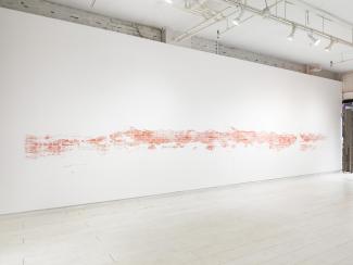 installation view of a long stencilled drawing in pink chalk on a single wall