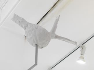 a wasp's nest made from layers of paper, installed on a metal post near the gallery ceiling