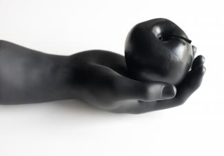 dark grey sculpture of a hand holding an apple