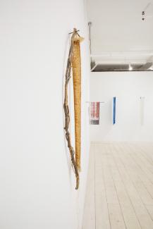 a sculptural textile object hanging on a white wall