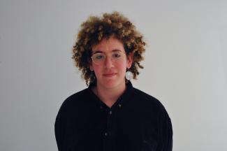 Person smizes in front of a white wall