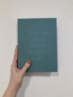 A book with a teal linen cover, embossed with the words "They are lost as soon as they are made"