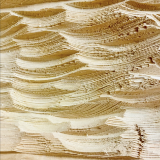 Image still of carved pale wood, the texture mimicking waves