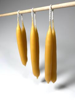 Image of hand-dipped beeswax candles hanging on a dowel