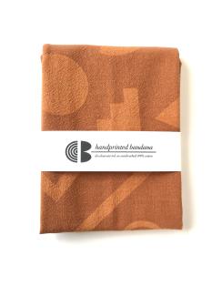 Image of a terracotta bandana, folded and wrapped with the artist's label