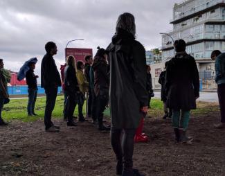 image of people standing to listen to a speaker on a walk outside in grey weather